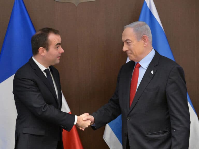 Prime Minister Benjamin Netanyahu shakes hands with Sébastien Lecornu beside Israeli and French flags.