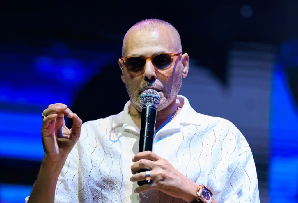 Israeli singer Yishai Levy speaks into a microphone on stage.
