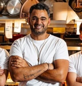 Chef Raz Shabtai stands in a restaurant kitchen.