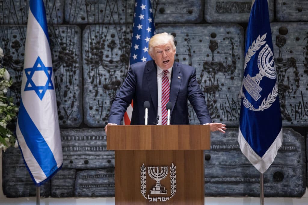 President Donald Trump speaks at a podium in Jerusalem with Israeli and American flags behind him.