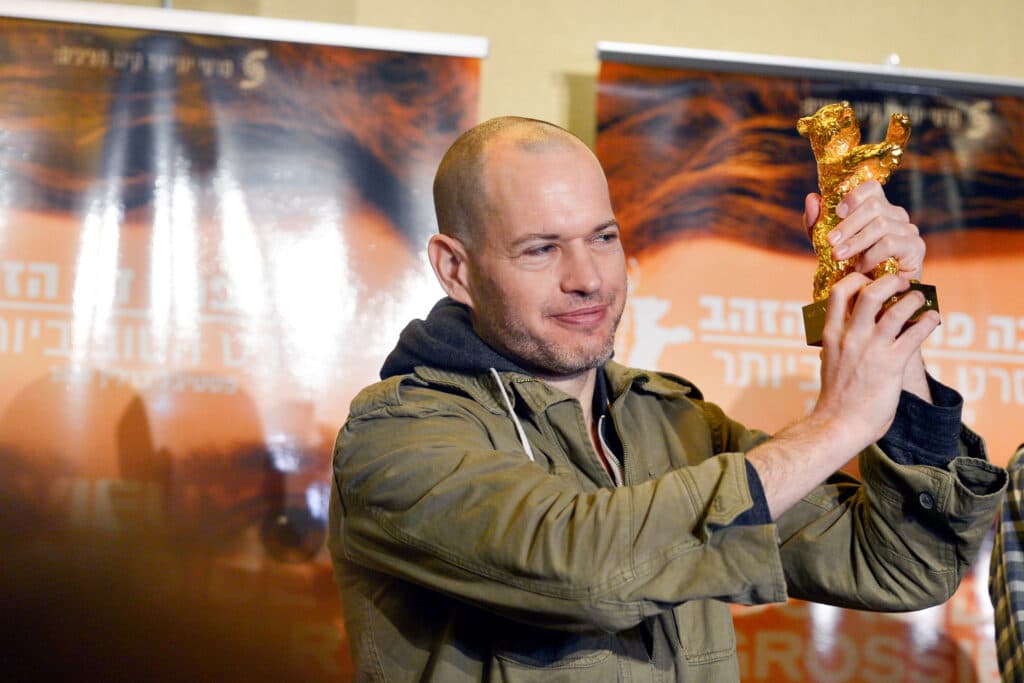 Israeli director Nadav Lapid holding a Golden Bear award during a press conference.
