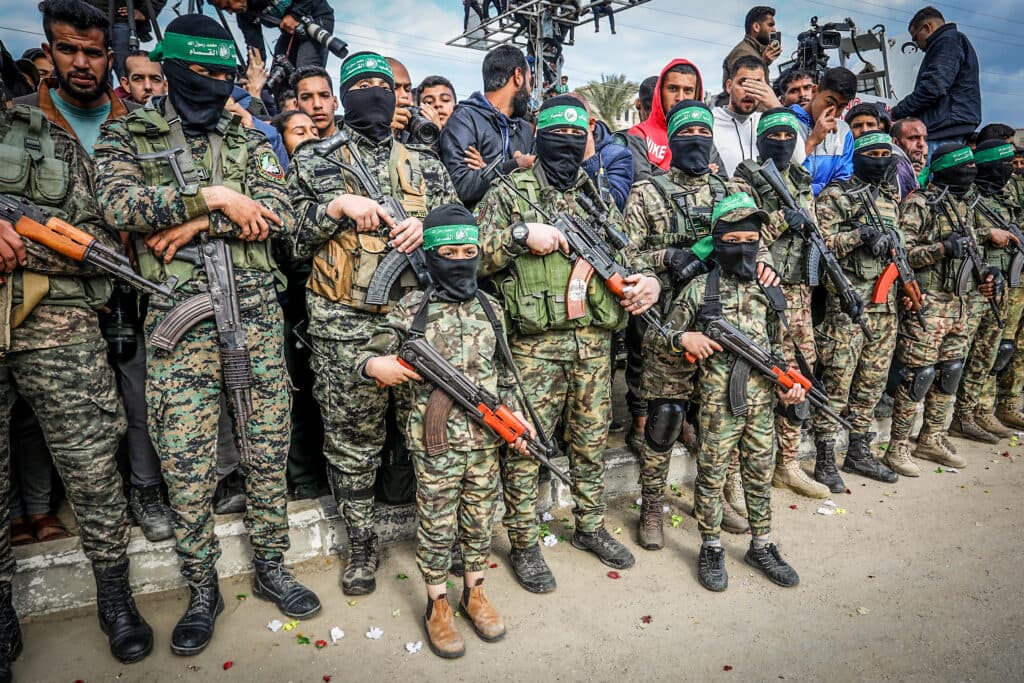 Palestinian children dressed in Al-Qassam Brigade uniforms carry weapons in Deir al-Balah.