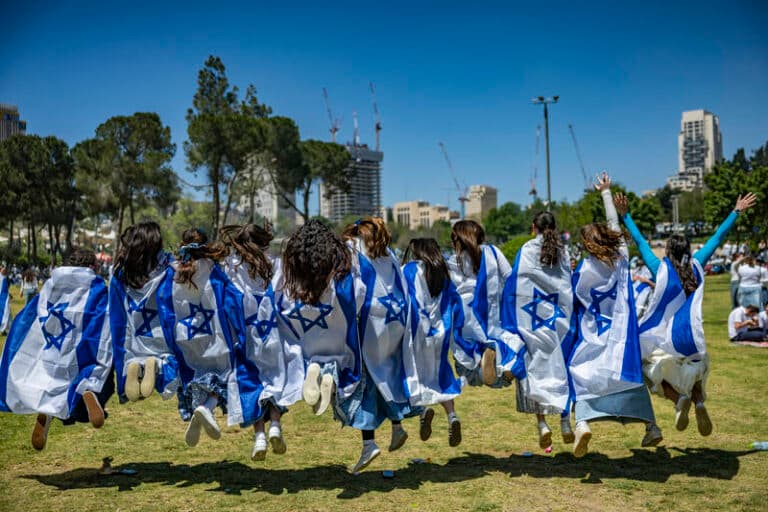 Girls jumping in air wrapped in Israeli flags in celebration of Israel Independence Day, 2026