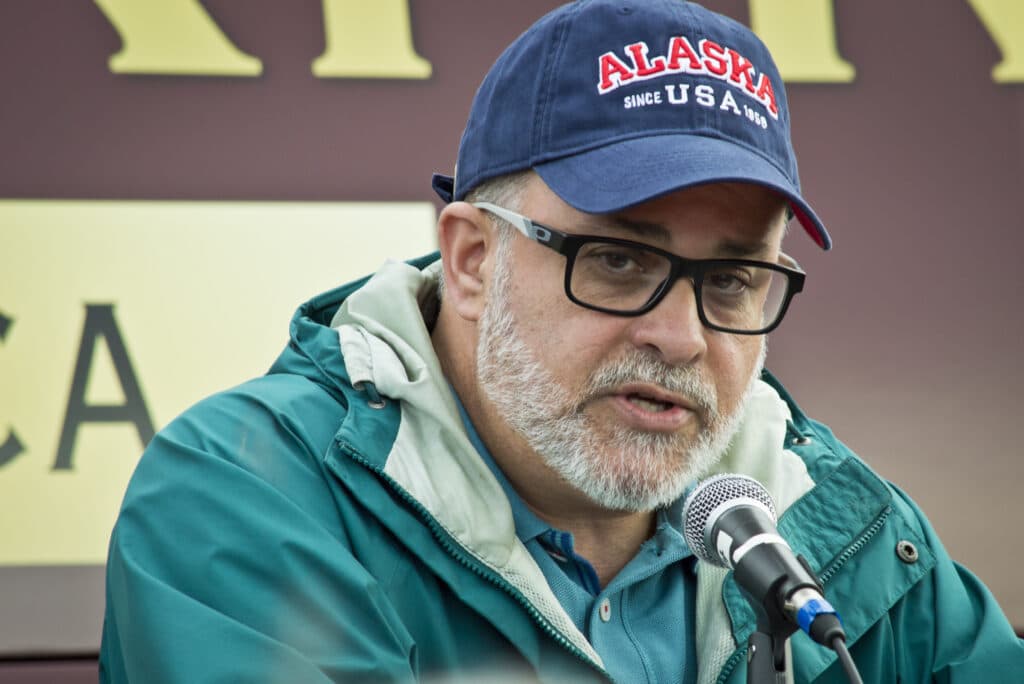 Mark Levin speaks into a microphone while wearing an Alaska baseball cap.