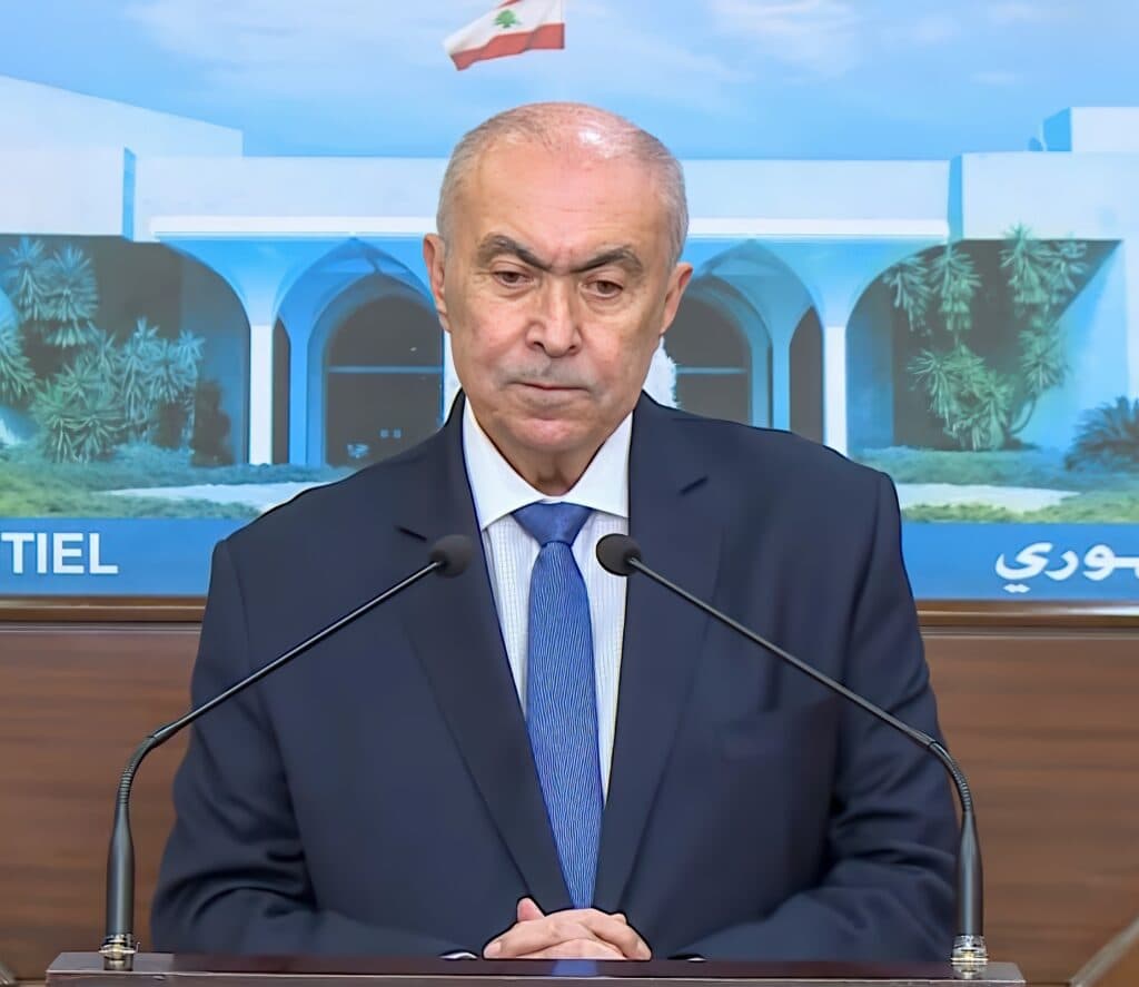 Lebanese lawmaker Fouad Makhzoumi speaking at a podium with the Lebanese flag behind him.