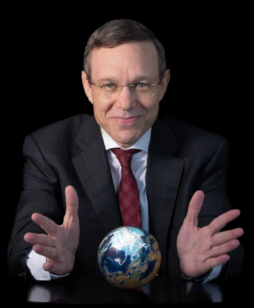 Avi Loeb sitting behind a globe against a black background.