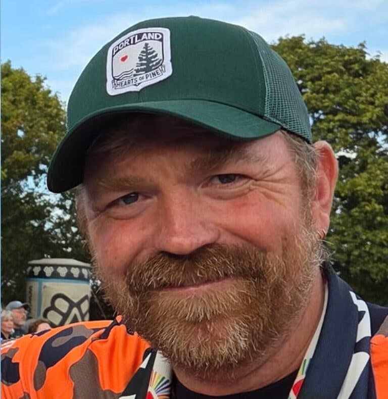 Graham Platner wearing a green cap in an outdoor headshot.