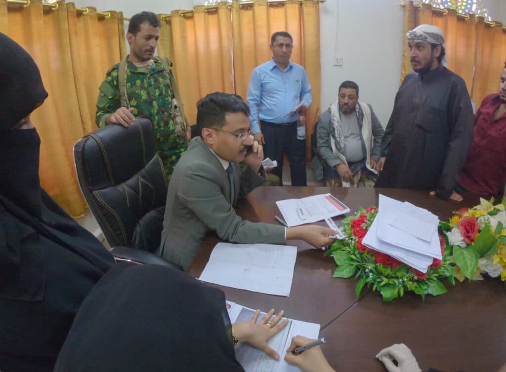 Yemeni officials and security personnel gather around a desk in a government office.