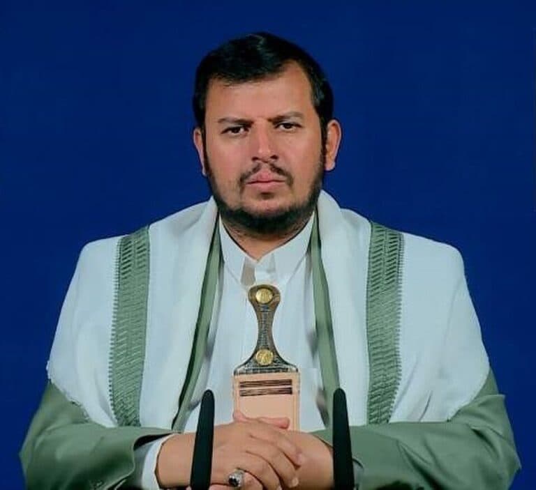 Abdul Malik Badr al-Din al-Houthi seated in front of a blue background.