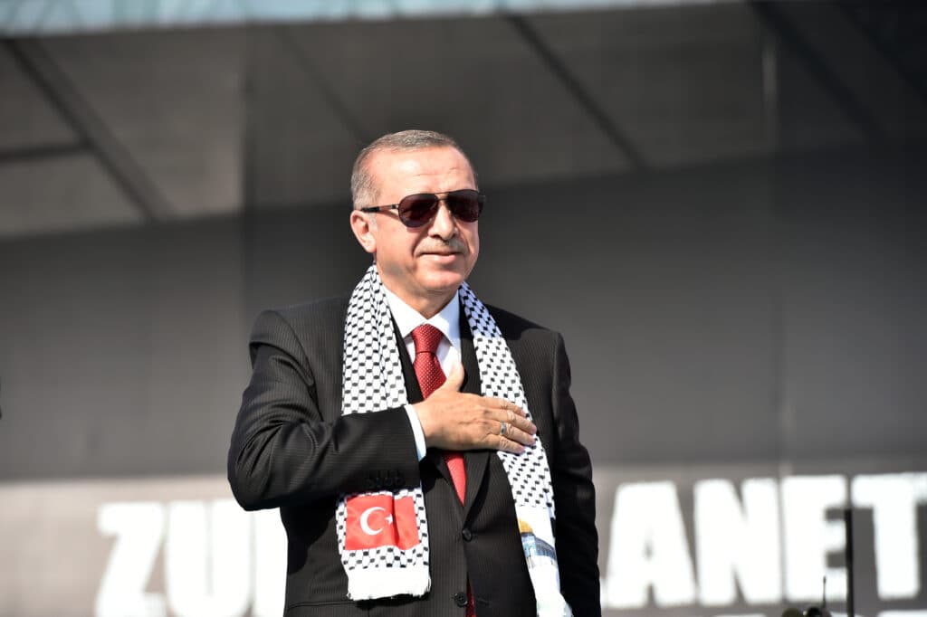 Turkish President Recep Tayyip Erdoğan wearing sunglasses and a Turkish-Palestinian scarf at a public event.