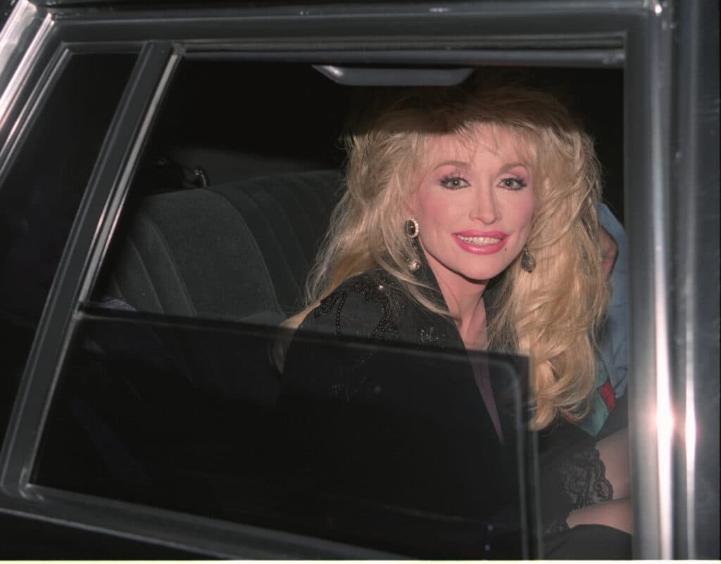 Dolly Parton smiling while seated inside a car.