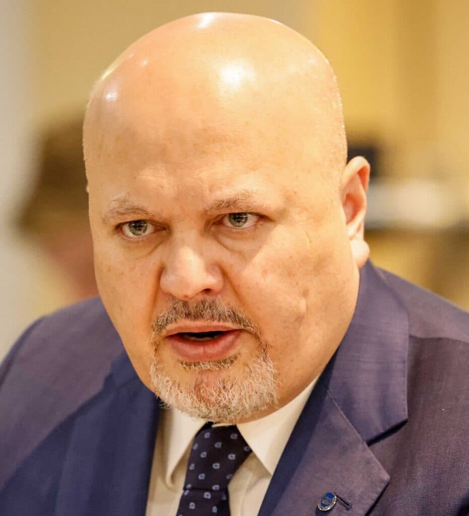 Karim Khan speaking while wearing a suit and tie.