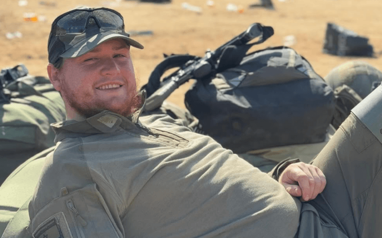 Staff Sgt. Moshe Shmuel Noll smiles while resting outdoors in uniform.
