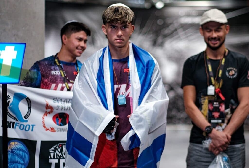 Ahavat Hashem Gordon standing with an Israeli flag draped over his shoulders.