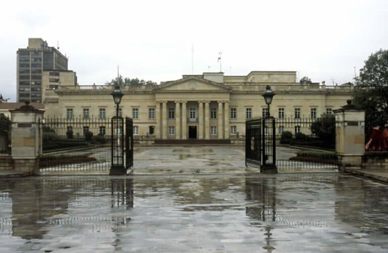 The presidential palace in Bogotá, Colombia, seen behind open gates on a rainy day.