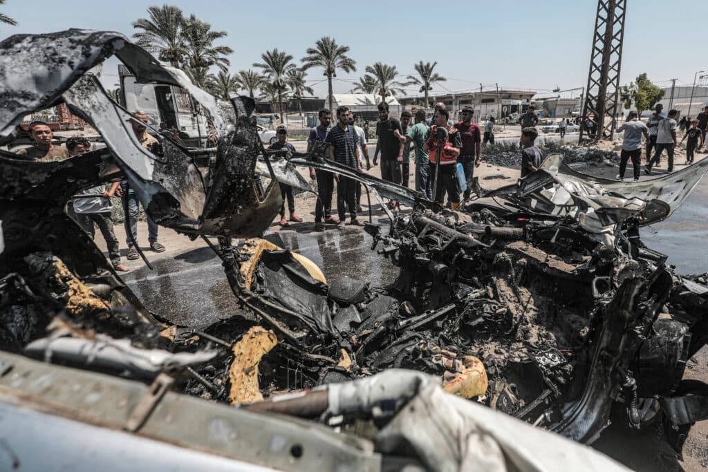 Palestinians gather near the wreckage of a vehicle after an Israeli strike in central Gaza.