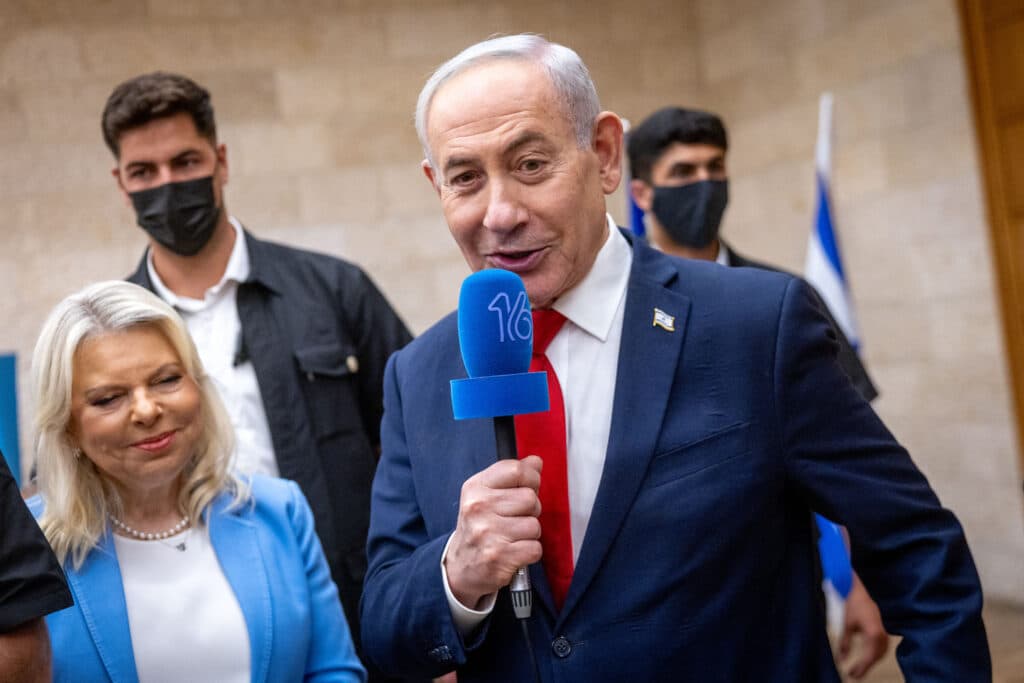 Prime Minister Benjamin Netanyahu holding a microphone beside Sara Netanyahu at a Likud primary polling station.