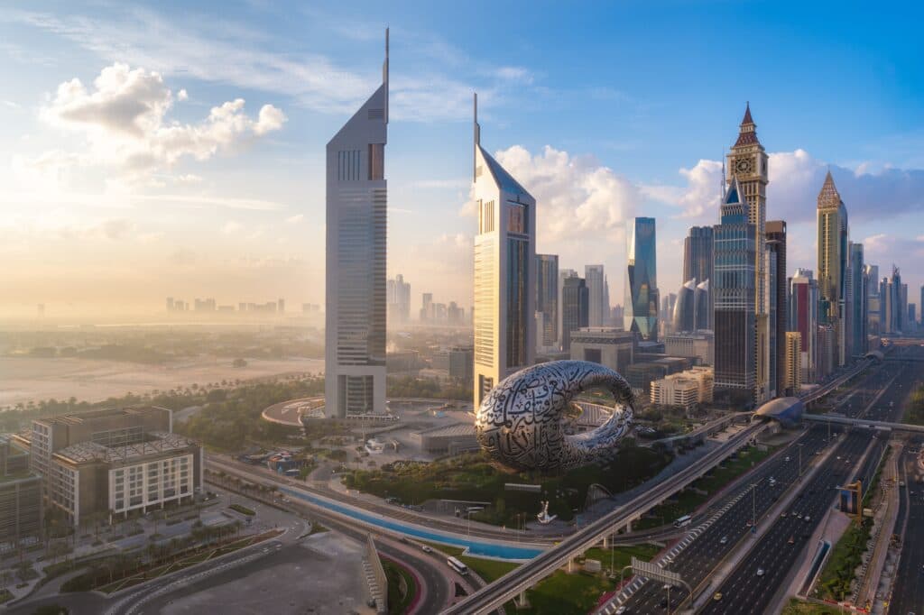 The Dubai skyline with modern towers and highways at sunrise.
