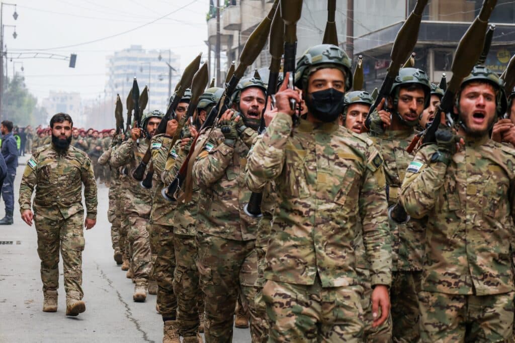 Armed Syrian soldiers marching in formation with rocket-propelled grenade launchers.