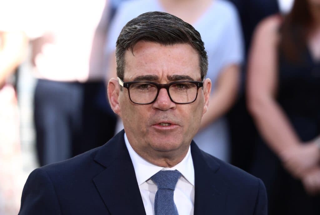 UK Prime Minister Andy Burnham speaking outdoors in a dark suit and glasses.