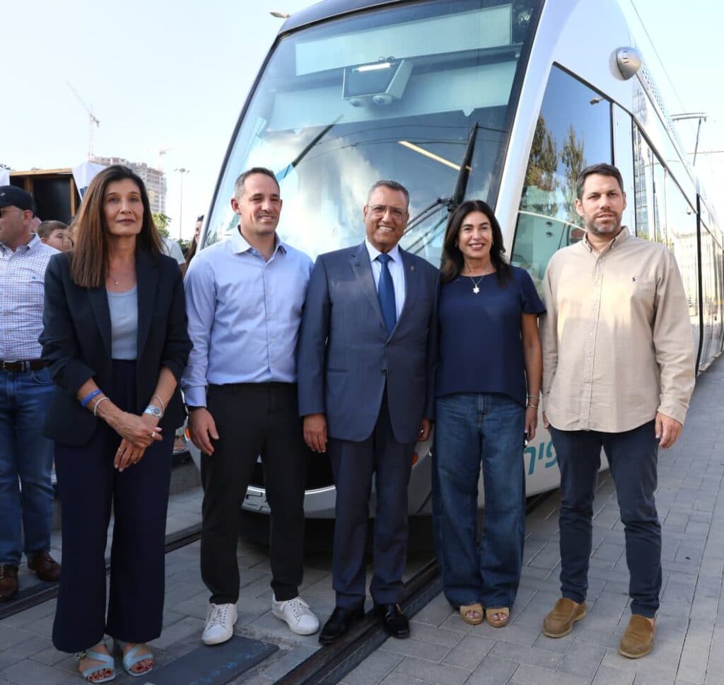 Officials standing in front of a Jerusalem light rail train at a station.
