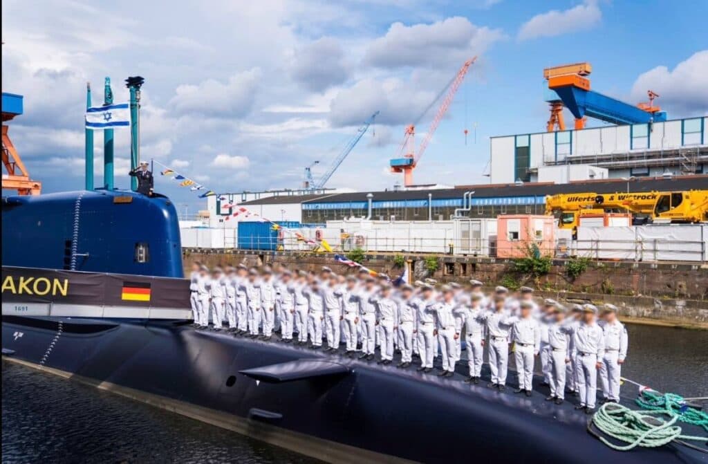 INS Drakon submarine at the TKMS shipyard in Kiel, Germany, with Israeli Navy personnel standing on deck.