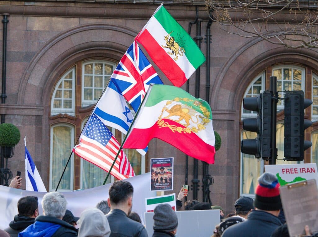 Flags of the United States, Israel, Iran, and the United Kingdom at a protest in Manchester.
