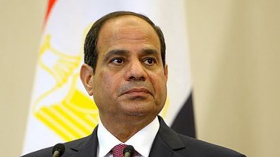Egyptian President Abdel Fattah el-Sisi stands at a podium with the Egyptian flag behind him.
