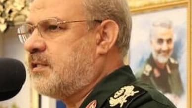 IRGC spokesman Hossein Mohebi speaks at a microphone in military uniform.