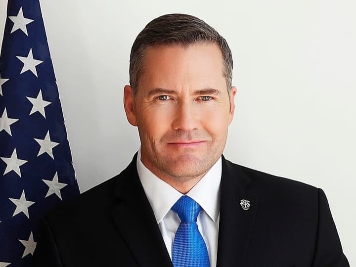 Official portrait of Mike Waltz standing beside the American flag.
