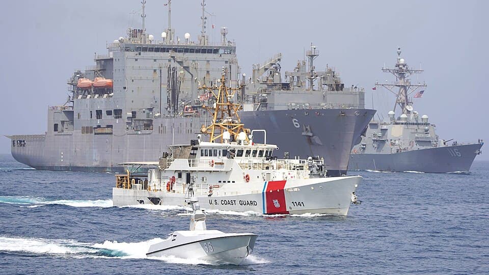 U.S. Navy and Coast Guard vessels transit the Strait of Hormuz behind an unmanned surface vessel.