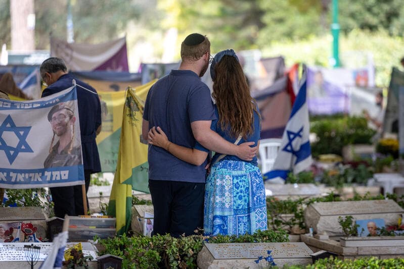 A couple embraces among graves of October 7 victims at Mount Herzl military cemetery in Jerusalem.