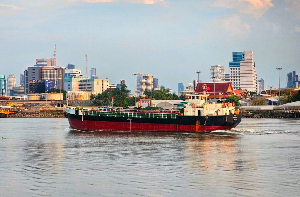 A commercial vessel sailing on the water near a city skyline.