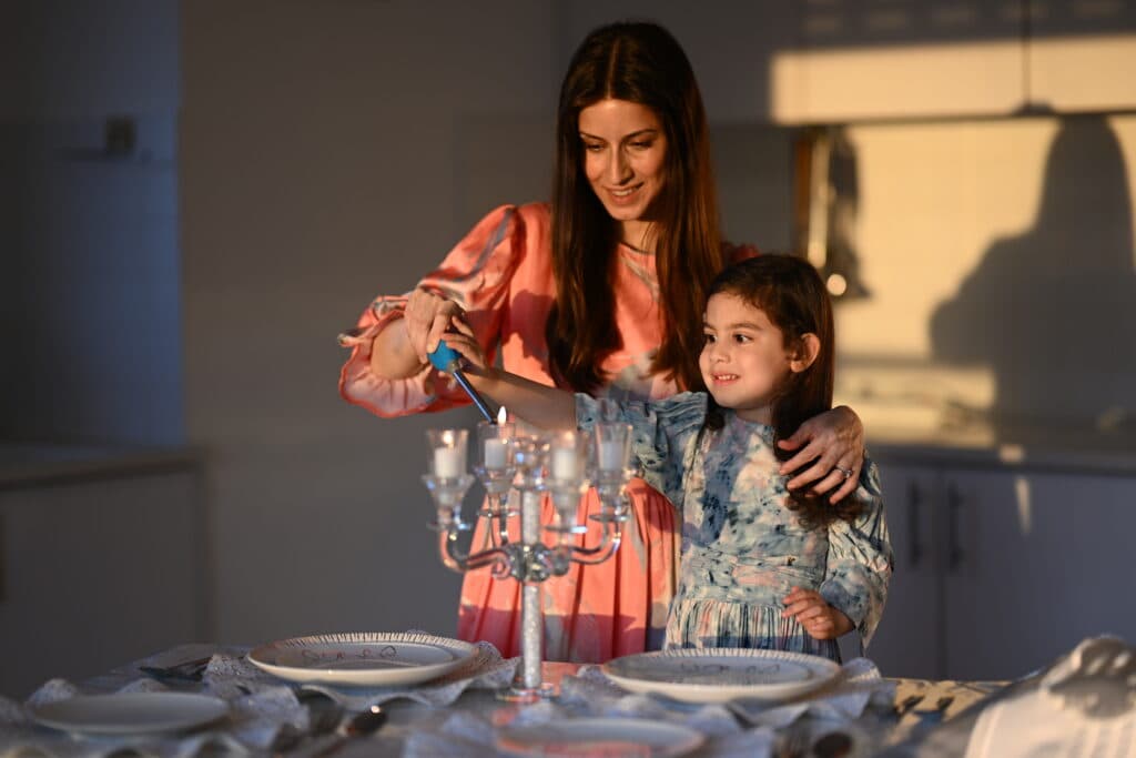 Mother and daughter lighting shabbat candles