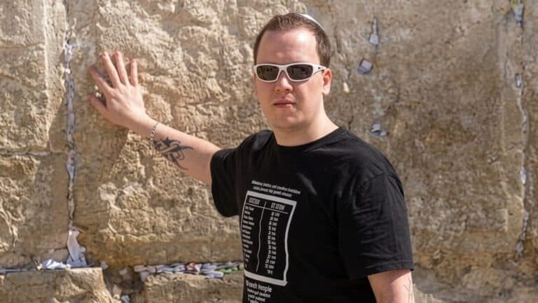 Swedish Christian influencer Andreas Fagerbakke standing with his hand on the Western Wall in Jerusalem.
